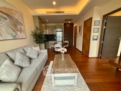 Modern living room with elegant decor and open kitchen layout, featuring cozy seating and stylish wooden flooring.