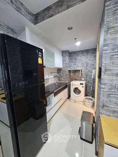 Modern kitchen with sleek appliances and washing machine in stylish apartment.