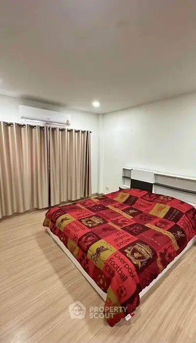 Spacious bedroom with modern decor and air conditioning, featuring a stylish bedspread and ample natural light.
