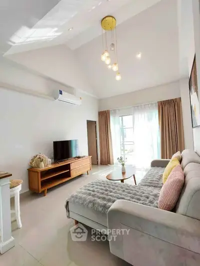 Spacious living room with modern decor and natural light, featuring a cozy sofa and stylish lighting.