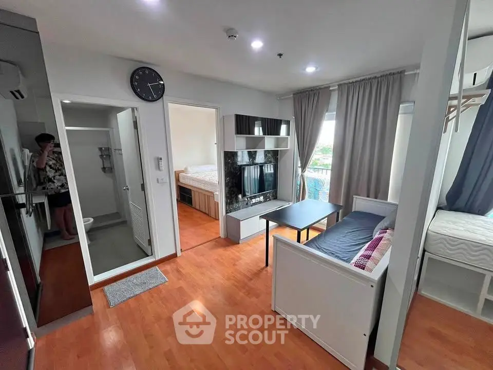 Modern studio apartment with wooden flooring, compact kitchen, and cozy bedroom area.