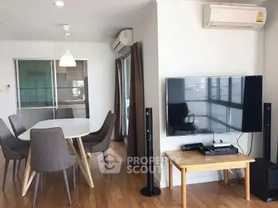 Modern living room with dining area and large TV, featuring sleek furniture and wooden flooring.