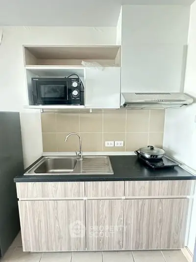 Modern compact kitchen with microwave and stovetop in sleek apartment