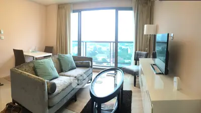 Spacious living room with modern furniture and large window offering stunning city views.