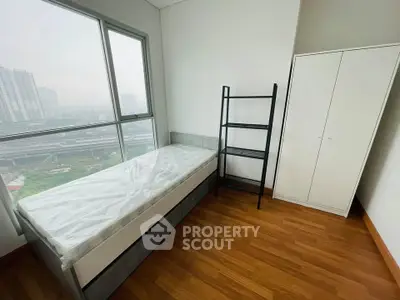 Modern bedroom with large window and city view, featuring a single bed and wardrobe.