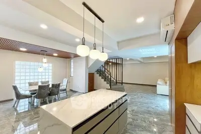 Spacious modern living room with open layout and elegant dining area, featuring stylish lighting and marble flooring.