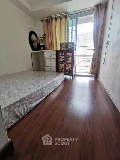 Cozy bedroom with wooden flooring and balcony access