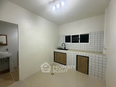 Minimalist kitchen with tiled backsplash and adjacent bathroom