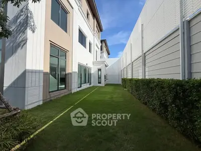Modern townhouse exterior with lush green lawn and clear blue sky.