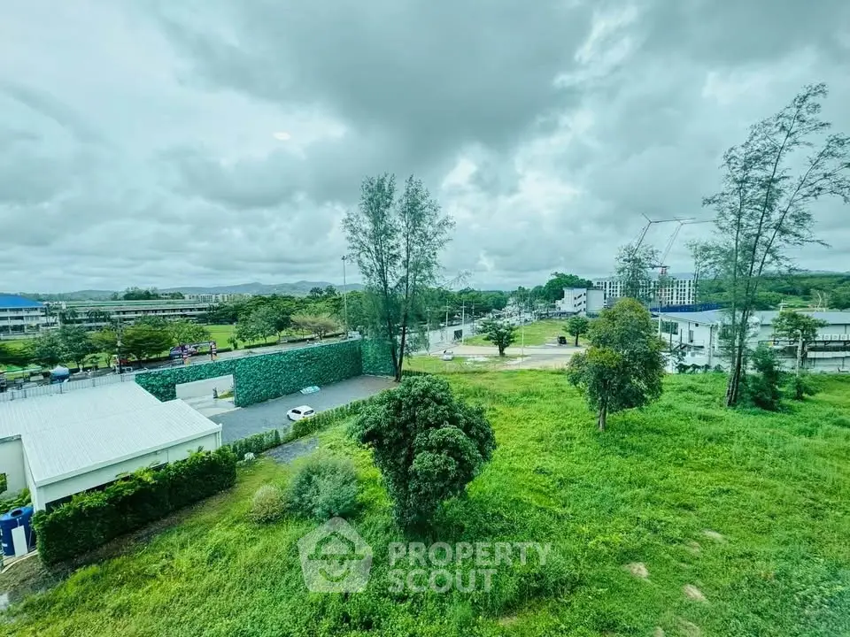Scenic view of lush green landscape with modern buildings under cloudy sky
