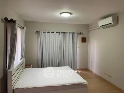 Spacious bedroom with natural light and modern air conditioning unit.