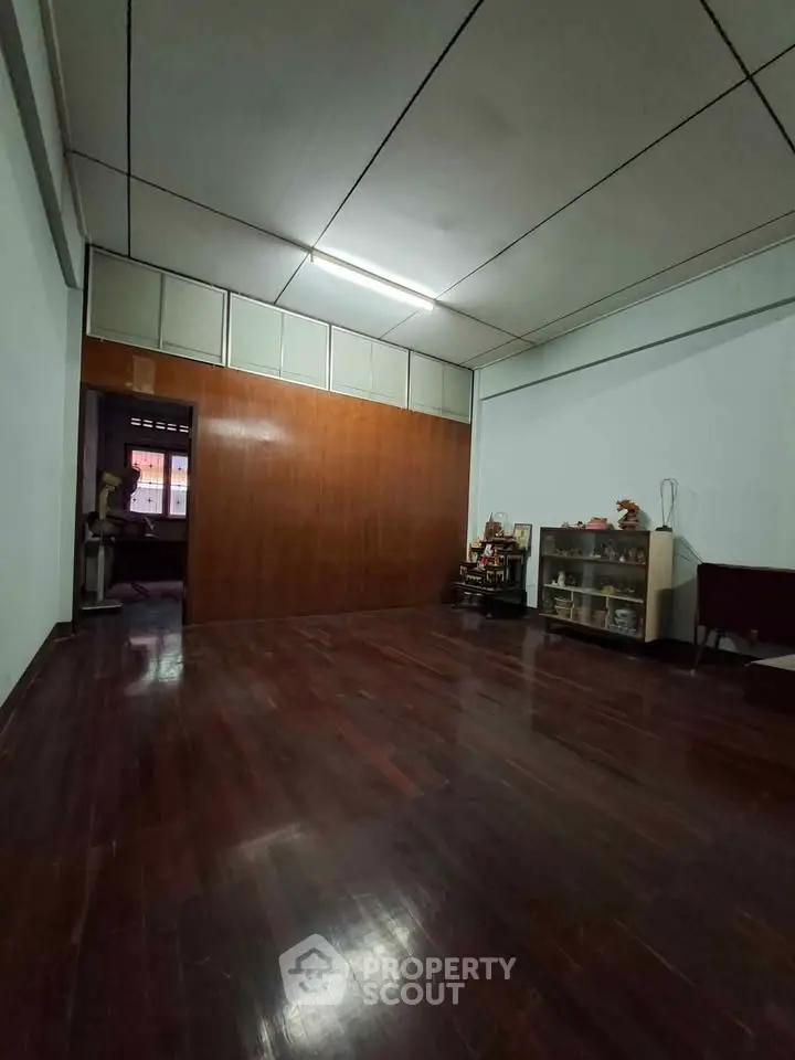Spacious room with wooden flooring and built-in shelving, ideal for versatile living space.