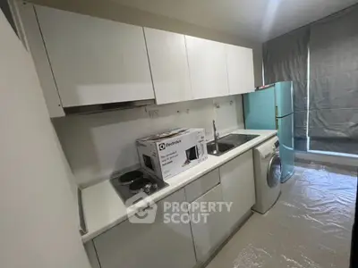 Modern kitchen with sleek white cabinets, washing machine, and Electrolux appliance box.