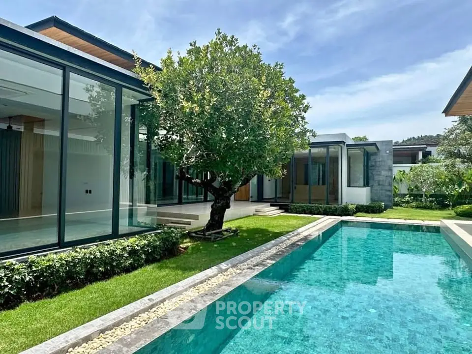 Luxurious modern villa with private pool and lush garden, featuring sleek glass architecture and serene outdoor space.