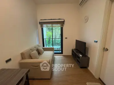Cozy living room with modern decor and garden view, featuring a comfortable sofa and flat-screen TV.