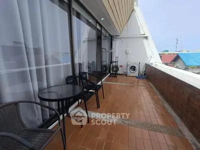Spacious balcony with seating and washing machine, ideal for relaxation and laundry convenience.