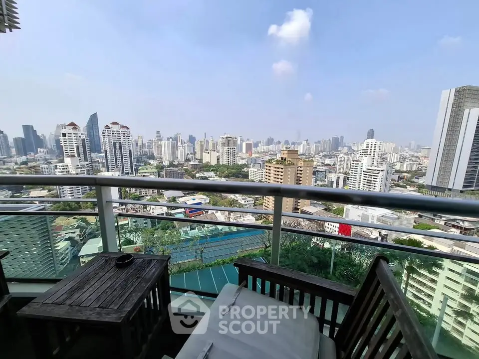 Stunning cityscape view from a high-rise balcony with cozy seating area, perfect for relaxation.