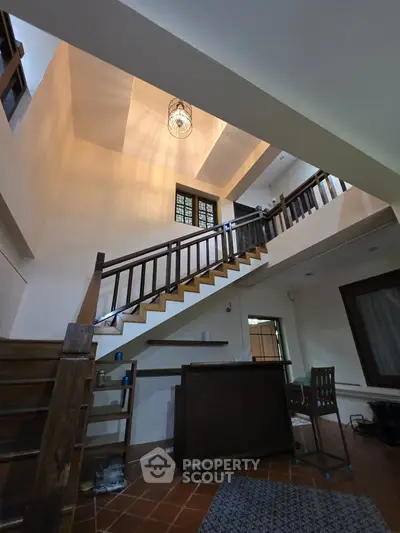 Spacious two-story living area with wooden staircase and modern lighting