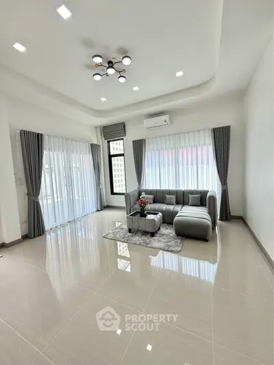 Spacious modern living room with elegant sofa and large windows for natural light.