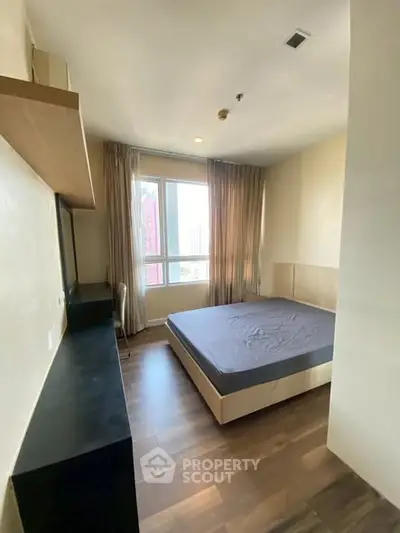 Modern bedroom with large window and wooden flooring in a high-rise apartment.