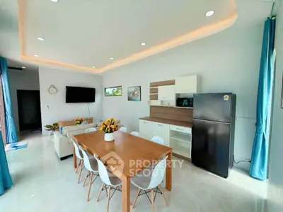 Modern open-plan living room with dining area and sleek kitchen appliances