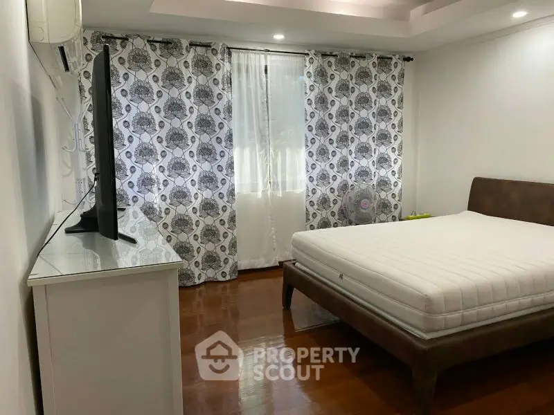 Spacious bedroom with modern decor and large window for natural light.