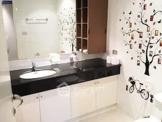 Charming bathroom with elegant black countertop and decorative wall art in modern apartment.