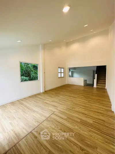 Spacious modern living room with wooden flooring and large window view