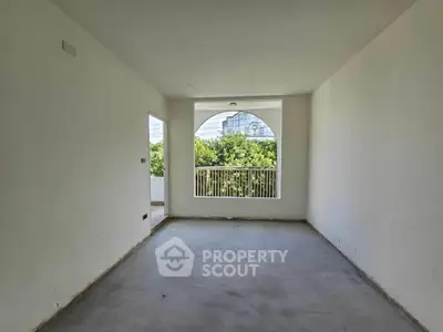 Spacious unfurnished room with large window and garden view, perfect for customization.