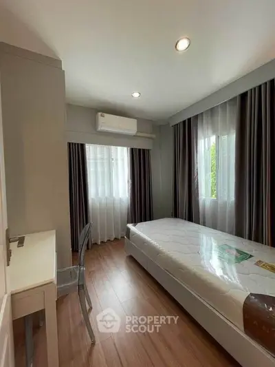 Modern bedroom with sleek design, featuring a single bed, wooden flooring, and ample natural light.