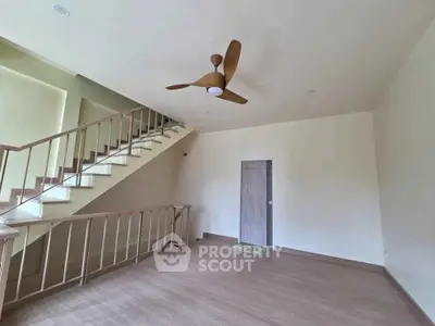 Spacious living room with modern ceiling fan and elegant staircase in a stylish home.