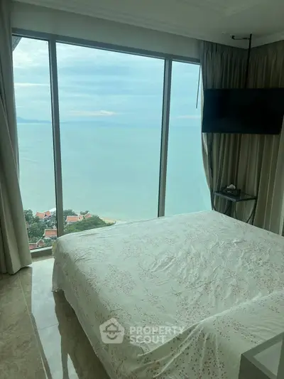 Luxurious bedroom with stunning ocean view from floor-to-ceiling windows.