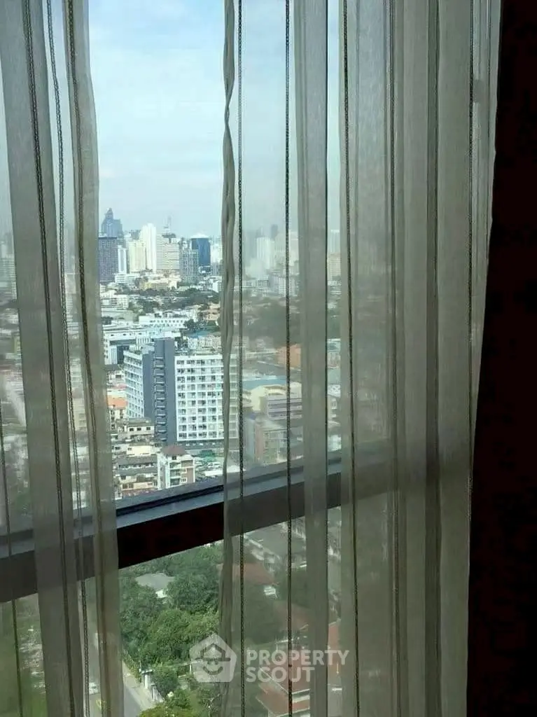 Stunning cityscape view through elegant sheer curtains in a high-rise apartment.