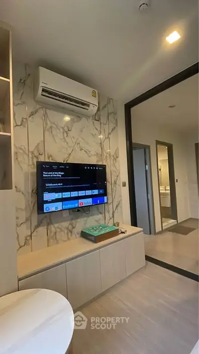 Modern living room with wall-mounted TV and air conditioning in stylish apartment.