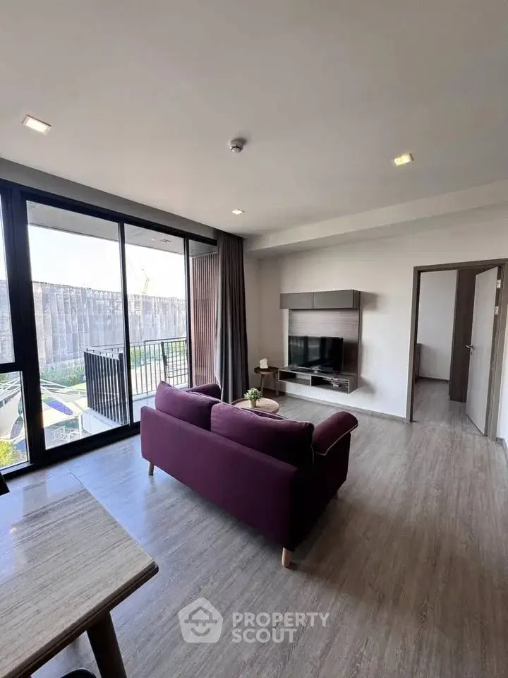 Modern living room with sleek design and large windows opening to a balcony.