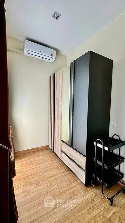 Modern bedroom with sleek wardrobe and air conditioning in a stylish apartment.