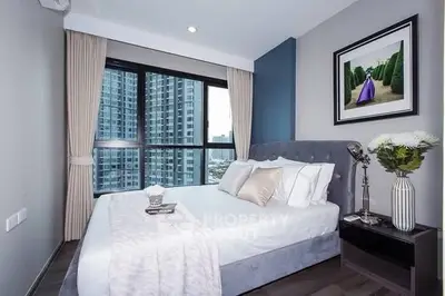 Modern bedroom with large window and city view, featuring elegant decor and cozy ambiance.
