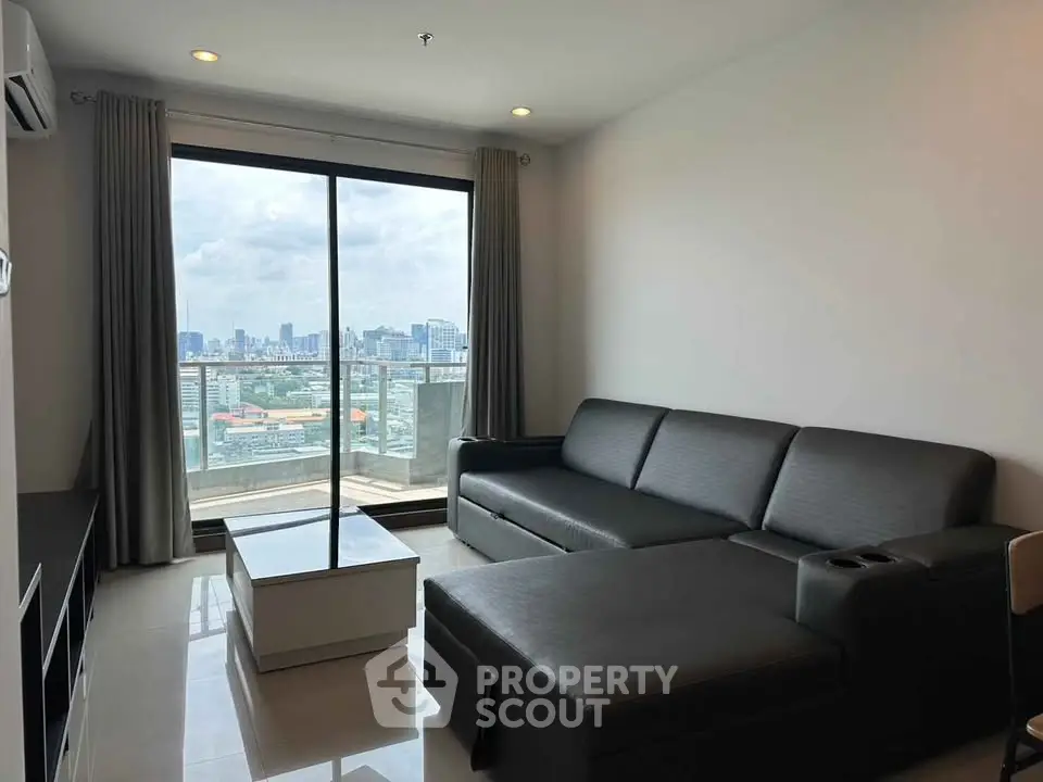 Modern living room with city view, featuring sleek black sofa and large windows for natural light.