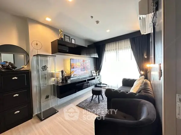 Modern living room with sleek black furniture and large window for natural light.