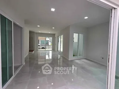 Spacious modern living room with large windows and glossy tiled floors in a contemporary home.
