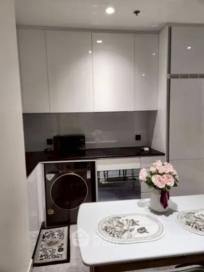 Modern kitchen with sleek cabinets, washing machine, and elegant dining setup.