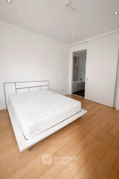 Spacious minimalist bedroom with wooden flooring and modern design.