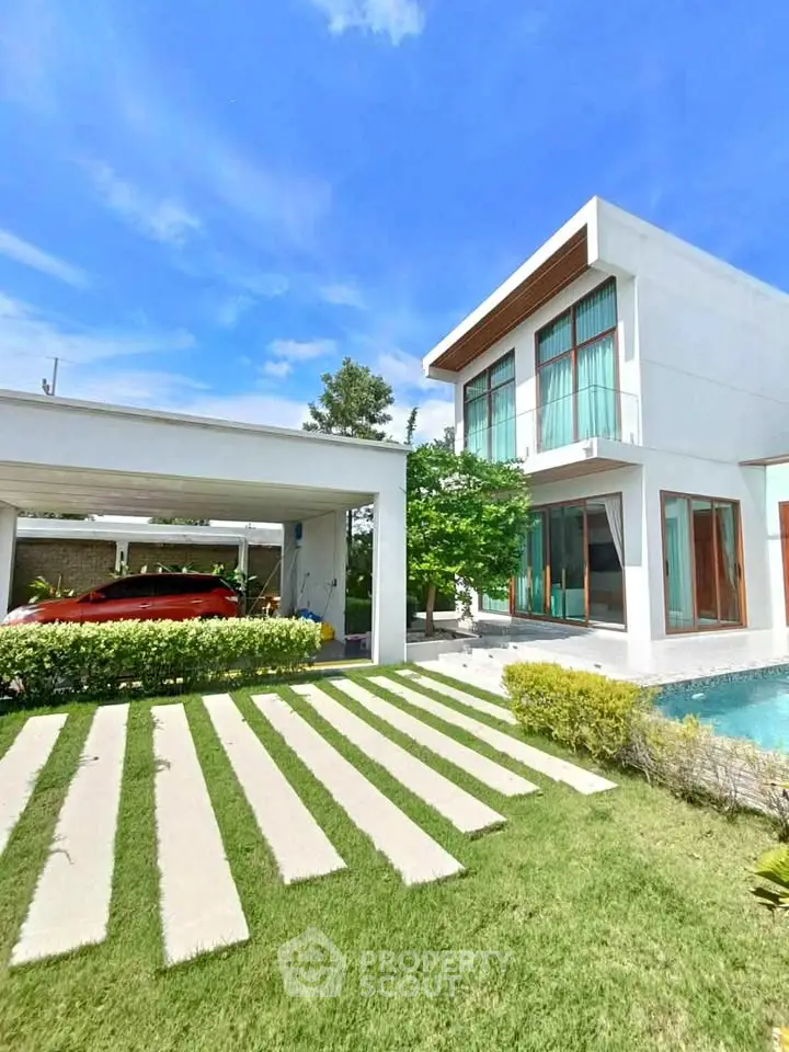 Modern luxury villa with pool and carport in a lush garden setting.