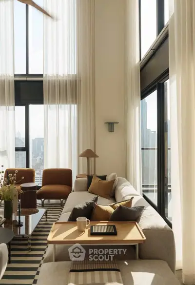 Luxurious high-ceiling living room with floor-to-ceiling windows and modern decor.