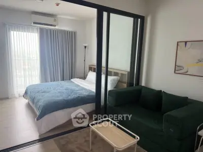 Modern studio apartment with glass partition, cozy bed, and stylish green sofa.