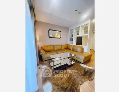 Stylish living room with leather sofa and glass coffee table on a chic rug.
