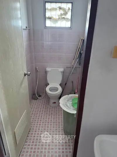 Compact bathroom with pink tiles and basic amenities