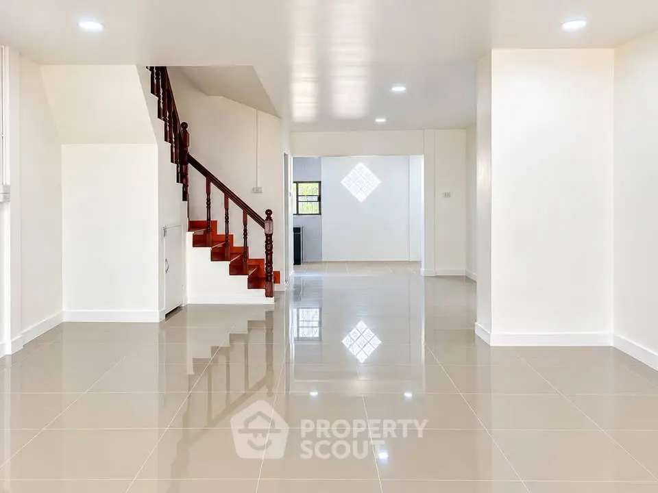 Spacious open-plan living area with glossy tiled floors and elegant staircase.
