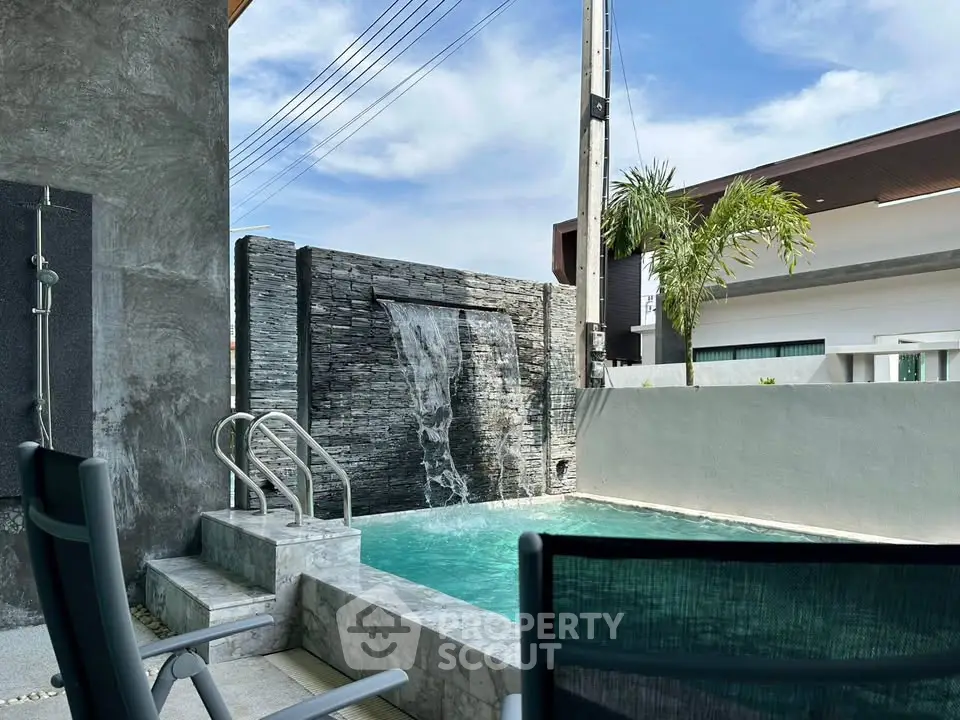 Luxurious private pool with waterfall feature in modern residential setting.
