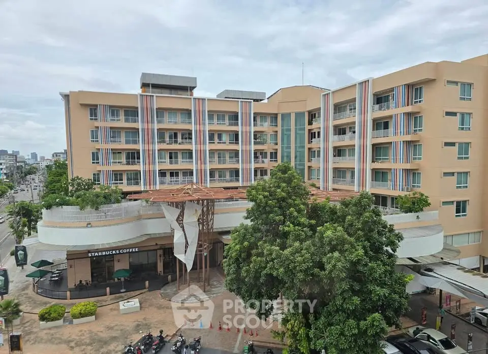 Modern multi-story building with commercial space and lush greenery in urban setting.